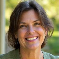 Portrait of Elara Thorne, a calm and wise-looking certified wellness coach, smiling gently in a natural outdoor setting