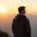 Liam K., a recent graduate, looking thoughtful and inspired by a scenic mountain vista